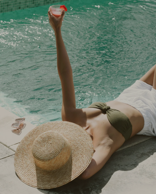 Chic poolside self-care moment with sun hat, swimwear, and cold drink
